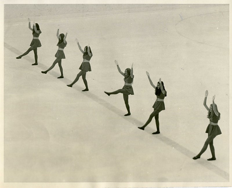 Pom pom team performing on ice during a period break at a hockey game, 1972