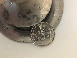Photo of a quarter lying near a bathtub drain